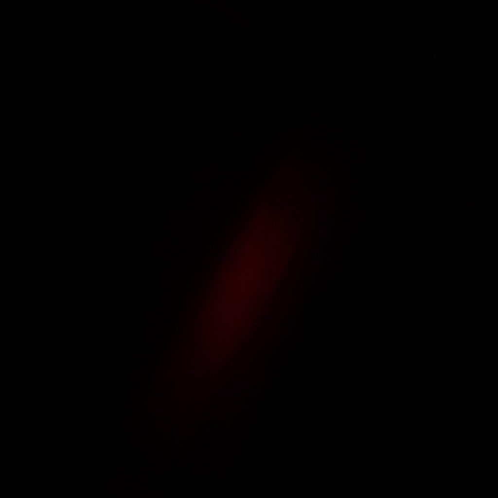 Тёмная фотография стопок свёрнутых тканей и кружева на прилавке, выполненная в приглушённых синих и серых тонах с глубокими тенями.
